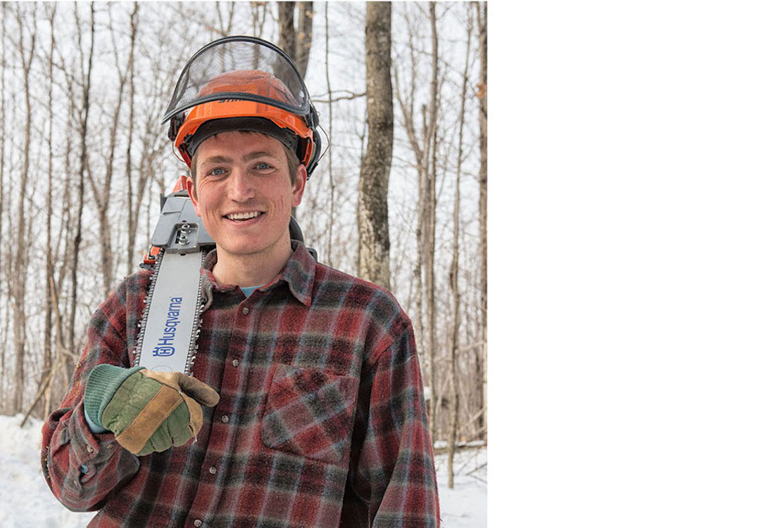 image of Thomas McCay (a young white man) wearing a hard hat. He is resting a chainsaw on his right shoulder.